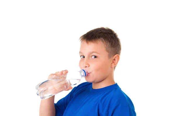 Criança bebe água limpa de garrafa isolada em fundo branco.O menino está vestindo uma camiseta azul — Fotografia de Stock