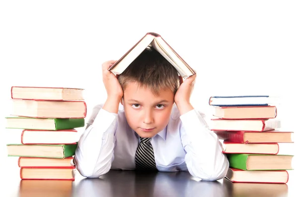 A unavený, zaostávající školák chlapec sedí v knihovně s knihami a učí se hodiny. Neochota se učit — Stock fotografie