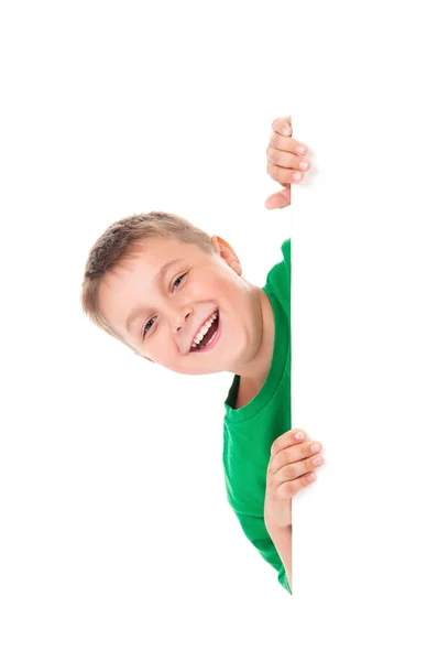 Emocional menino sorrindo positivo em camiseta verde brilhante e posando atrás de um painel branco isolado no fundo branco. Lugar para publicidade de banner — Fotografia de Stock