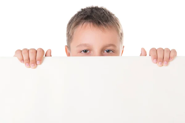 Sorridente bel ragazzo adolescente maschio in posa dietro pannello bianco su sfondo bianco. Spazio pubblicitario per poster da cartellone — Foto Stock