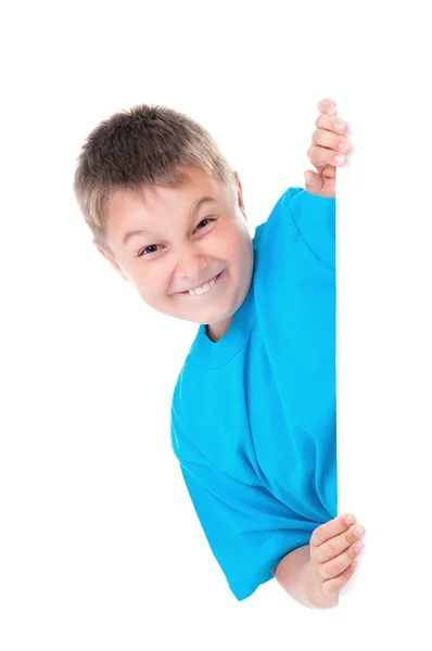 Ragazzo adolescente emotivo sorridente positivo in t-shirt blu brillante e posa dietro un pannello bianco isolato su sfondo bianco. Luogo per la pubblicità — Foto Stock