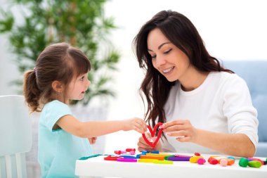 Gülümseyen anne ve küçük kızı plastikin kırmızı kalp Sculpt. Çocuk gelişimi ve yaratıcılık. Aile aşkı, mutlu çocukluk