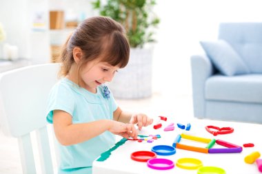 Gülümseyen küçük güzel kız plastikin yeni ev heykel. Çocuk yaratıcılığı. Mutlu çocukluk. Ev düşleri