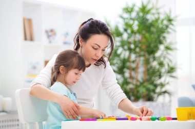 Anne, küçük bir kızına plastikin heykelleri şekillendirmesine yardımcı olur. Çocuk yaratıcılığı. Mutlu aile
