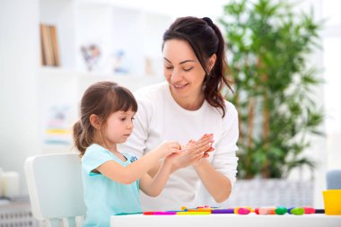 Anne, küçük bir kızına plastikin heykelleri şekillendirmesine yardımcı olur. Çocuk yaratıcılığı. Mutlu aile