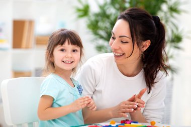 Gülümseyen anne plastikin gelen figürinler heykel için küçük bir kız yardımcı olur. Çocuk yaratıcılığı. Mutlu aile
