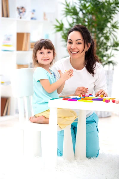 A mãe sorridente ajuda uma pequena filha a esculpir estatuetas de plasticina. Criatividade infantil. Família feliz — Fotografia de Stock