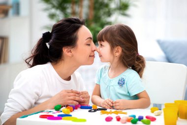 Annemin hassaslığı ve aşkı. Anne yavaşça burnunda kızını öpüyor. Hamuru gelen kadın ve küçük kız kalıp