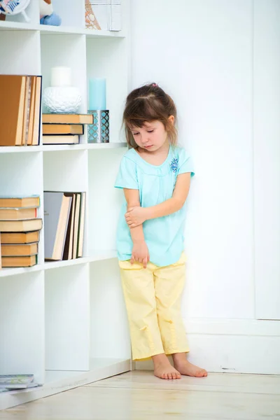 A sad little delinquent girl stands punished in the corner. Wines and punishment of children — Stock Photo, Image