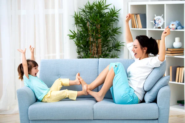 Мама і маленька дочка сидять на дивані, грати і веселяться. Щаслива сім'я та батьківство. Дозвілля з дітьми — стокове фото
