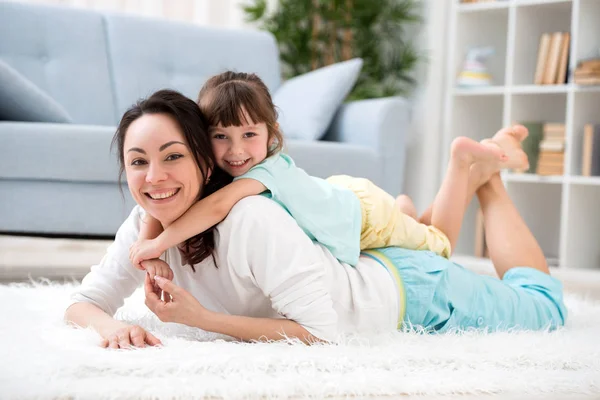 Счастливая семья. Мама с маленькой дочкой веселятся, играют в комнате на полу, обнимаются, улыбаются и веселятся — стоковое фото