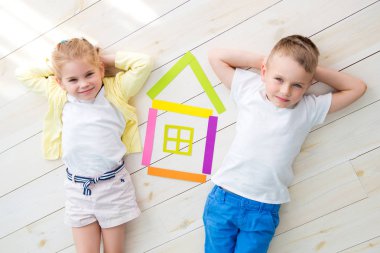 Çocuk yalan renkli kağıttan bir evin yanındaki katta küçük bir kızla. Yukarıdan görüntülemek