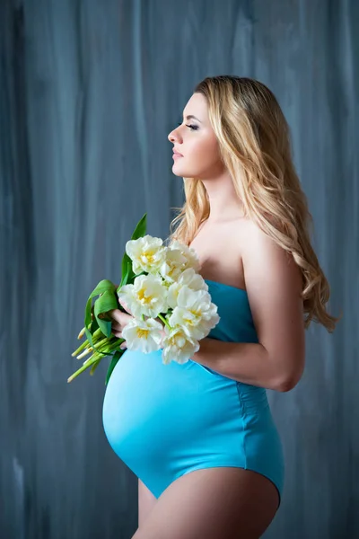 Beautiful young pregnant blonde woman holding flowers white tulips in her hands. Spring mood, freshness, women's Day, health and beautiful pregnancy — Stock Photo, Image