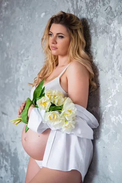 Frumos tineri gravidă blondă femeie dragoste flori lalele albe. Stare de spirit de primăvară, prospețime, Ziua Femeii, sănătate și sarcină frumoasă — Fotografie, imagine de stoc