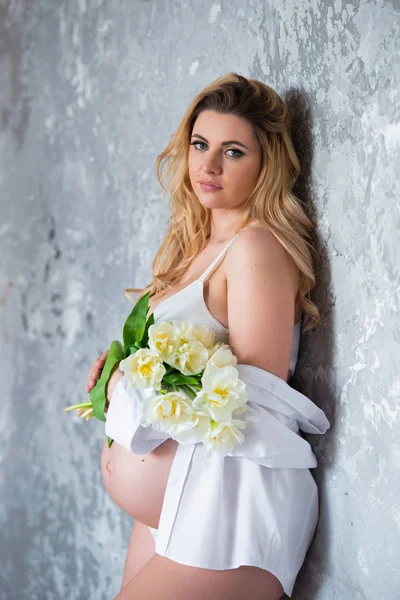 Bella giovane donna bionda incinta ama i fiori tulipani bianchi. Umore primaverile, freschezza, festa della donna, salute e bella gravidanza — Foto Stock