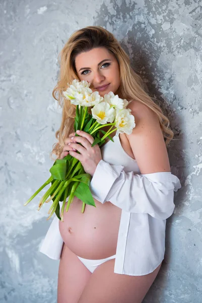 Mooie jonge zwangere blonde vrouw liefde bloemen witte tulpen. Lente stemming, frisheid, Vrouwendag, gezondheid en mooie zwangerschap — Stockfoto