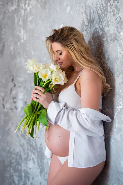 Frumos tineri gravidă blondă femeie dragoste flori lalele albe. Stare de spirit de primăvară, prospețime, Ziua Femeii, sănătate și sarcină frumoasă — Fotografie, imagine de stoc