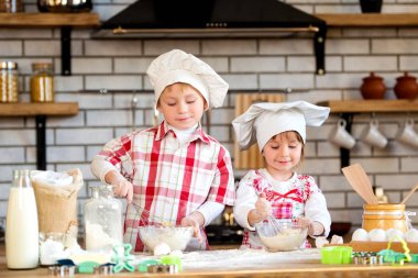 Çocuklar bir çocuk ve bir kız un ve yumurta bir hamur yoğurmak ve mutfakta lezzetli Gingerbread ve kurabiye hazırlamak