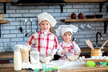 Çocuklar bir çocuk ve bir kız un ve yumurta bir hamur yoğurmak ve mutfakta lezzetli Gingerbread ve kurabiye hazırlamak