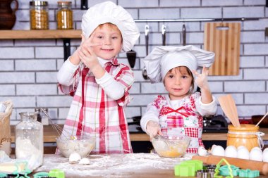 Çocuklar bir çocuk ve bir kız un ve yumurta bir hamur yoğurmak ve mutfakta lezzetli Gingerbread ve kurabiye hazırlamak