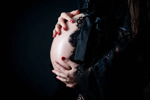 妊娠中の腹を優しく抱えた女性の白黒画像は、胎児に注意深く向き直る。妊娠と幸せな母性の概念 — ストック写真