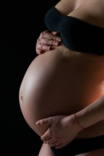 Imagem em preto e branco da mulher segurando ternamente a barriga grávida atentamente voltando-se para o feto. Conceito de gravidez e maternidade feliz — Fotografia de Stock