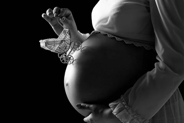 Zbliżenie kobiety w ciąży brzuch z zabawka wózek. Dziewczyna delikatnie trzyma brzuch z dzieckiem. Koncepcja ciąży, miłości matki i szczęśliwego macierzyństwa — Zdjęcie stockowe