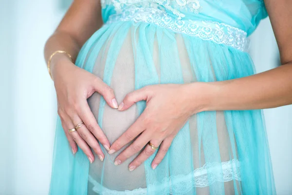 Родительская любовь и счастливое материнство. Крупный план формы сердца на фоне беременного живота — стоковое фото