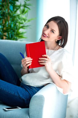 evde kırmızı bir not kitabı ile kız