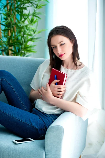 Dreaming girl with pen writing on notebook — Stock Photo, Image