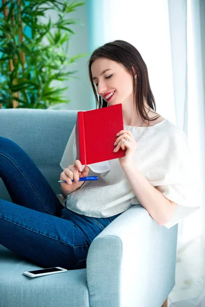 Girl with a red note book at home — Stock Photo, Image