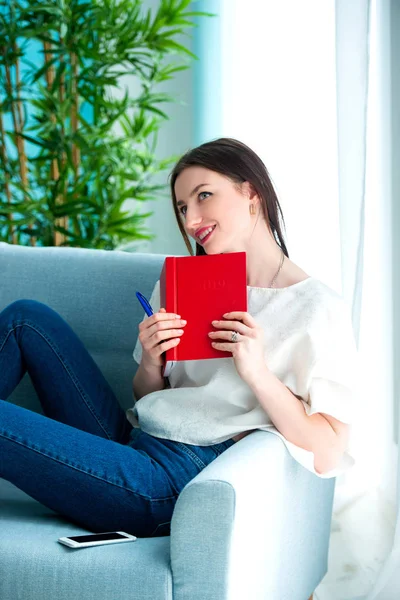 Girl with a red note book at home — Stock Photo, Image