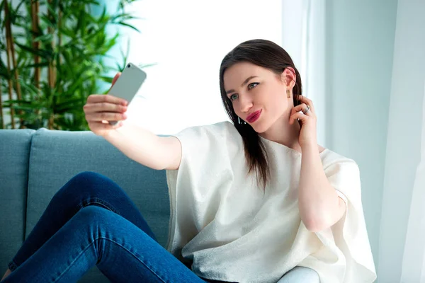 Young girl is making selfie at sofa. — Stock Photo, Image