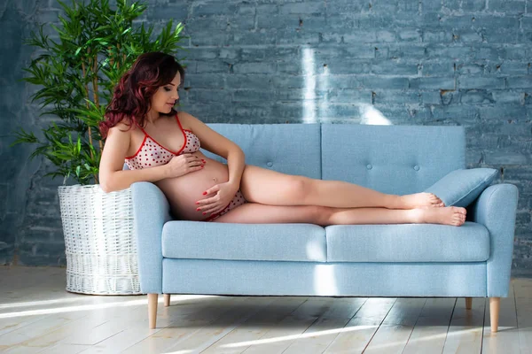 Close-up of a pregnant girl woman sitting on the sofa near the indoor plants. Healthy motherhood and happy pregnancy — Stock Photo, Image