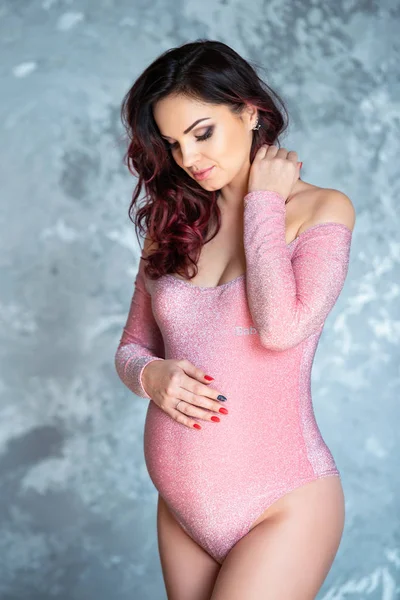 Güzel genç hamile esmer kadın gri beton duvar arka plan karşı poz — Stok fotoğraf