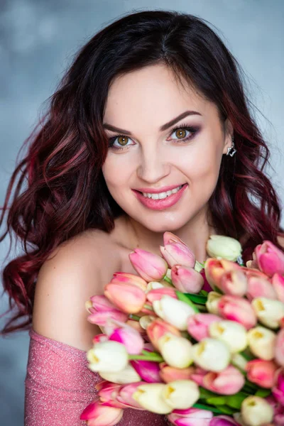 Beautiful young smiling girl with bouquet of spring flowers of tulips. The best gift is flowers for a birthday and womens day — Stock Photo, Image