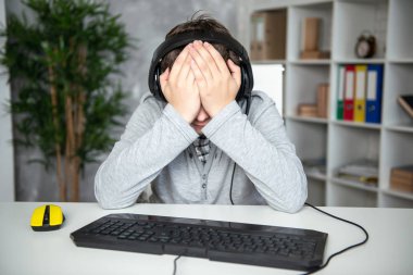Oops, başarısızlık, kayıp. Genç çocuk bir bilgisayar oyununda kaybetti. Bir öğrenci bir bilgisayar monitörü önünde üzgün oturur, elleriyle yüzünü kaplayan