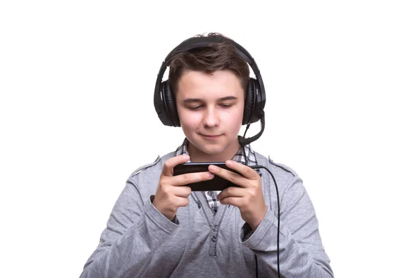 Schoolboy guy teenager with headphones playing a game on mobile phone. Gambling, telephone addiction — Stock Photo, Image