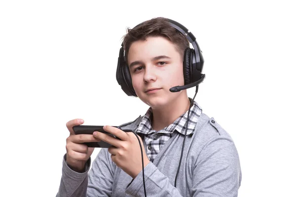 Schoolboy guy teenager with headphones playing a game on mobile phone. Gambling, telephone addiction — Stock Photo, Image