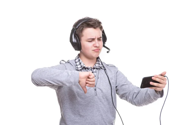 Schoolboy guy with headphones playing on mobile phone. Teenager happy screams . Young man won an online game on a smartphone. Cheers to the winner — Stock Photo, Image