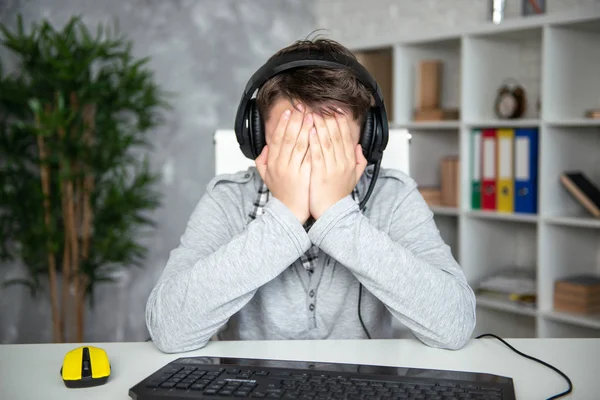 Oops, başarısızlık, kayıp. Genç çocuk bir bilgisayar oyununda kaybetti. Bir öğrenci bir bilgisayar monitörü önünde üzgün oturur, elleriyle yüzünü kaplayan