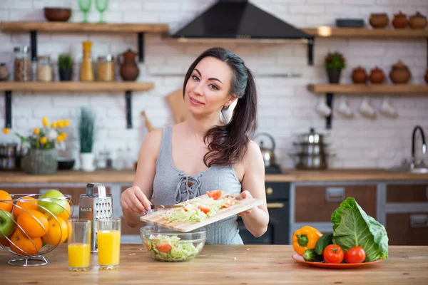 Güzel genç kadın mutfakta sebze salatası kesme