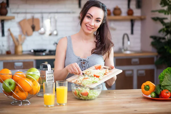 Güzel genç kadın mutfakta sebze salatası kesme
