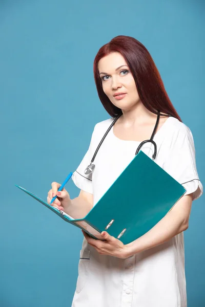 Family female woman doctor with a stethoscope holds folder with documents, has friendly expression, isolated blue background. Medicine concept