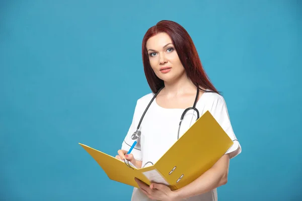 Family female woman doctor with a stethoscope holds folder with documents, has friendly expression, isolated blue background. Medicine concept