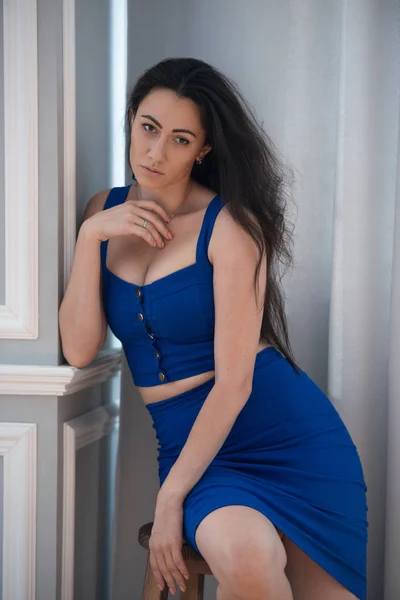 Office romance in the workplace. Seductive businesswoman secretary in blue dress sitting on a wooden stool — Stock Photo, Image