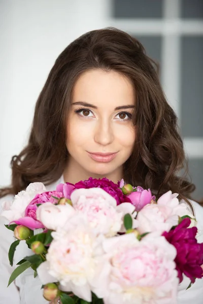 ゴージャスな髪とピオニーの花の花束を持つ美しい若い女性の女の子のクローズアップ肖像画 — ストック写真