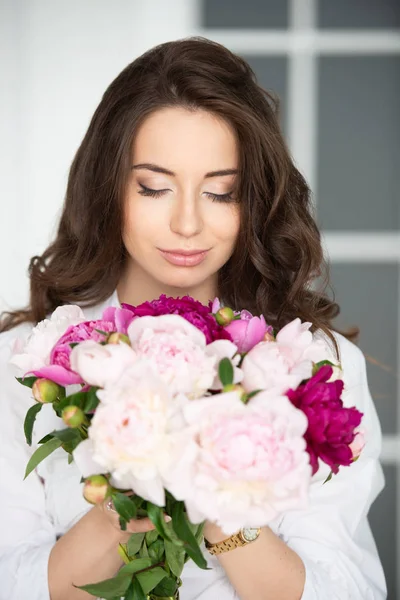 Close-up portrait of a beautiful young woman girl with gorgeous hair and a bouquet of peony flowers — Stock Photo, Image