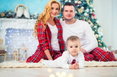Noel ağacı ve Yeni Yıl şömine yakınında damalı pijama mutlu gülümseyen aile