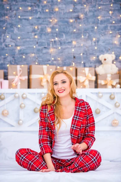 Красивая молодая блондинка в клетчатой пижаме с новогодними подарками. С Рождеством и Новым годом! — стоковое фото